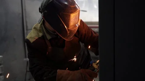A man (man at the factory)  in a protective mask works with a welding machine. Stock Footage 196879543