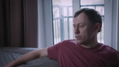 Man, the man sits reflectively on the sofa, unstable emotion-tonal state Stock Footage 310044988