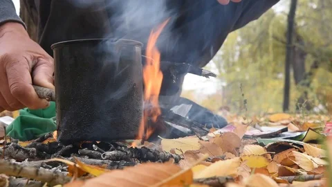 A man, a man is warming tea on a fire. Autumn, fallen leaves. Bonfire and flame. Stock Footage 101355930
