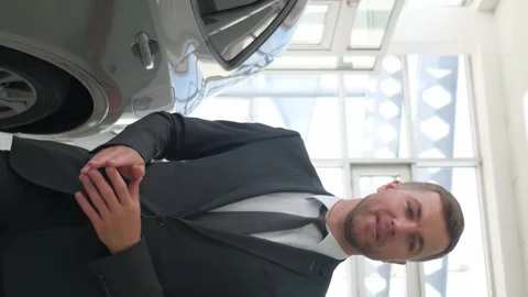 A man-manager of a car salon talks about new cars. Sale of cars in the Stock-Footage 250351564