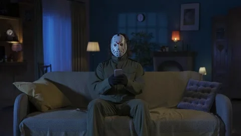 Man maniac sitting on the sofa in the someones living room, holding smartphone Stock Footage 250008605