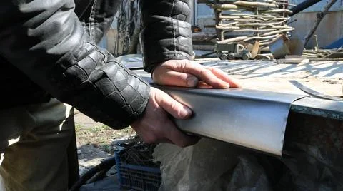 A man manually bends an iron plate on a workbench 库存照片