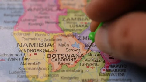 Man Marking Botswana Location with Green Pin on Paper World Map Stock Footage 333574625