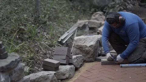 Man marking bricks for a decorative two tone paver soldier course pattern along Stock Footage 81993877