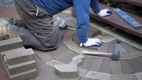 Man marking bricks for a decorative two tone paver pattern in front a stairway. Stock Footage 81996822
