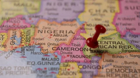 Man Marking Cameroon Location with Red Pin on Paper World Map Stock Footage 333577965
