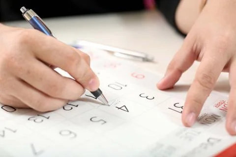 Man is marking a date on the calendar for the schedule with the pen Stock Photos