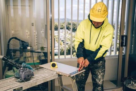 Man marking marks with pencil on a tile to be cut. Laying ceramic floor tiles Stock Photos