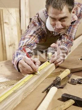 Man marking piece of timber using pencil and tape measure Stock Photos