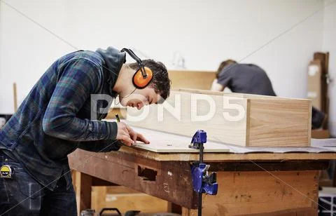 A man marking a piece of wood with a pencil. Stock Photos