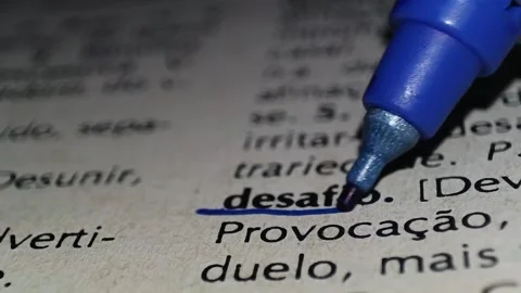 A man marks the definition from the word challenge in portuguese  on a printed p Stock Footage 297276951