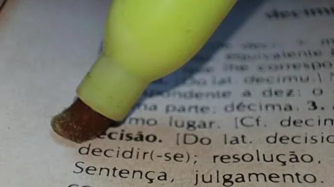 A man marks the definition from the word decision in portuguese  on a printed pa Stock Footage 297276935