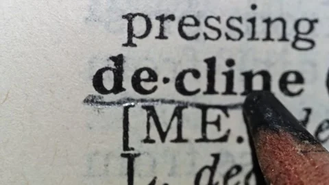 A man marks the definition from the word decline on a printed page with a pencil Stock-Footage 297276976