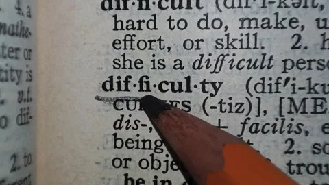 A man marks the definition from the word difficulty on a printed page with a pen Stock Footage 297278242