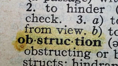 A man marks the definition from the word obstruction on a printed page with a ma Stock Footage 297282641