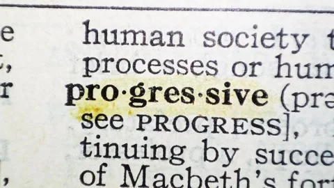 A man marks the definition from the word progressive on a printed page with a ma Stock Footage 297282727