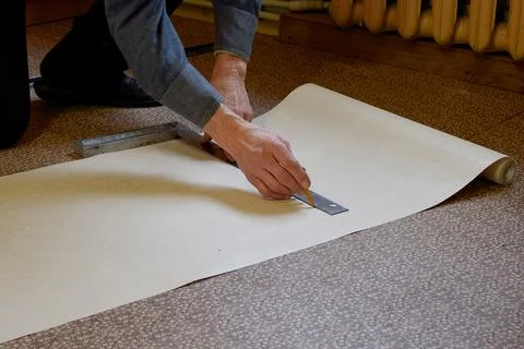 A man marks out wallpaper using a square and pencil. Stock Photos