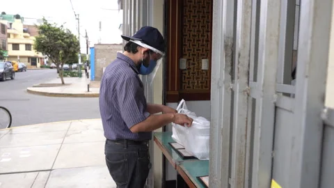 A man with a mask and face shield picking up his bagged food order  Stock Footage 140604817