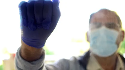 Man in a mask and globes outside the window trying to contact Stock Footage 129337547