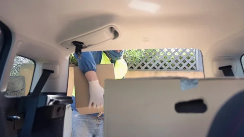 Man with mask and gloves loading packing in car Stock Footage 130152120