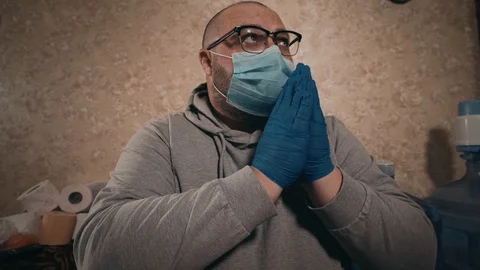 Man in mask and protective gloves prays for cessation of coronavirus, supplies Stock Footage 127603853