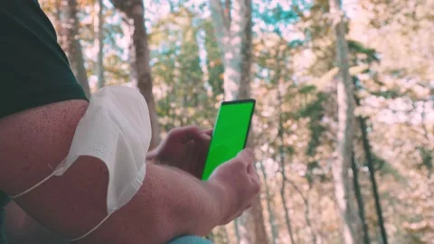 Man with mask in arm scrolling on his mobile phone in the park Video stock 140802698
