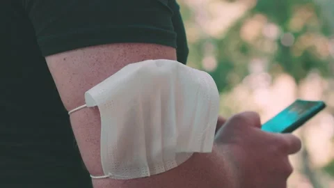 Man with mask in arm typing on his mobile phone Stock Footage 140873181