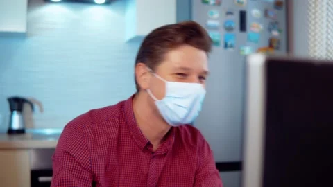 A man in a mask at a computer at home sings and has fun Stock Footage 144987006