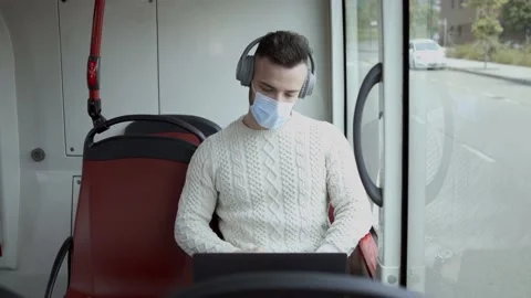 A man in a mask with the computer traveling on a public transport Stock Footage 130385190
