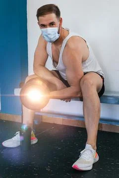 Man with mask doing biceps exercises with dumbbells in the gym. sitting on a Stock Photos
