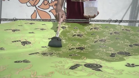 A man with the mask is doing the liquid immersion into the batik Stock Footage 146741045