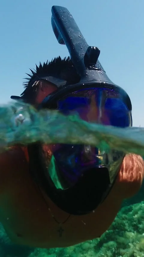 Man in the mask floats on the water surface in the sea. View over and under.. Stock Footage 280657994