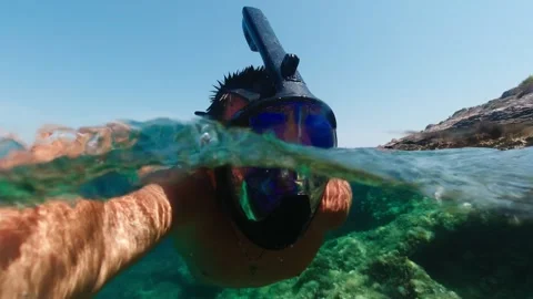 Man in the mask floats on the water surface in the sea. View over and under.. Stock-Footage 281630757