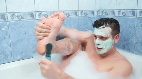 Man with mask on his face is peeling his foot sitting in bathroom at home. Stock Footage 158385004