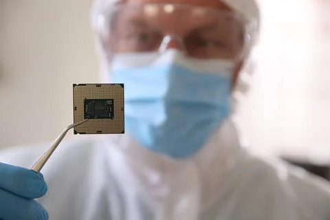 Man in mask holding computer chip on blurred background, selective focus Foto stock