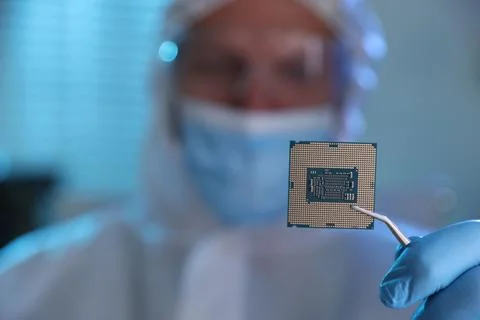 Man in mask holding computer chip on blurred background, selective focus Stock Photos