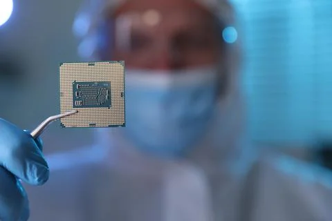 Man in mask holding computer chip on blurred background, selective focus Stock-Fotos