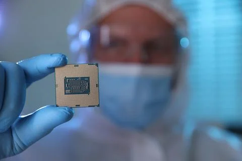 Man in mask holding computer chip on blurred background, selective focus 스톡 사진
