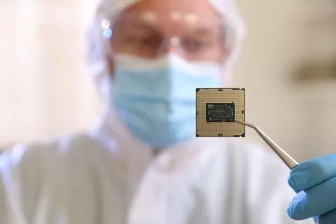 Man in mask holding computer chip on blurred background, selective focus 스톡 사진