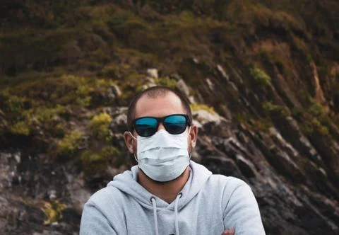 Man in mask looking at the beach looking out at the sea Stock Photos