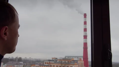 Man in mask looks through window at factory stack, environmental disaster Stock Footage 299659897