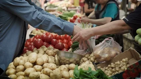 Man in mask puts cucumbers into bag at farmer market closeup Video stock 133737493