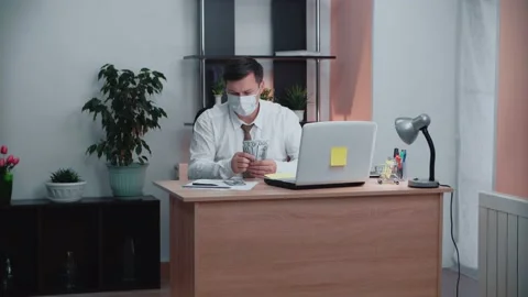 A man in a mask sitting at the table is counting money. Stock Footage 147668165