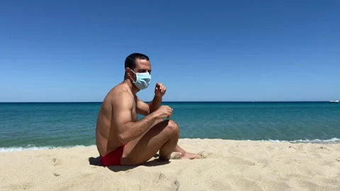 Man with mask sunbathing on the beach Stock Footage 132667975