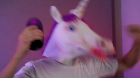 The man in the mask of a unicorn dancing with a column in hand Stock Footage 128998282