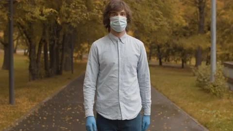 Man in mask walking in the park Stock Footage 141288193