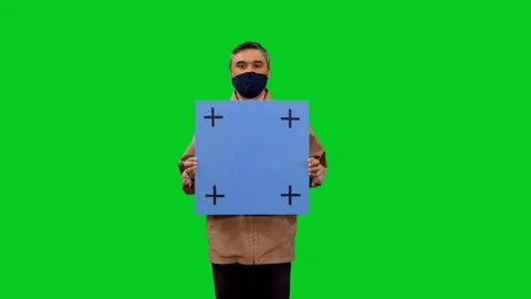 Man in mask walking towards the camera with blue blank board in hands 스톡 동영상 130796699