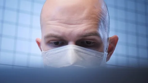 Man in mask works on computer studying coronavirus infection Stock Footage 124616431