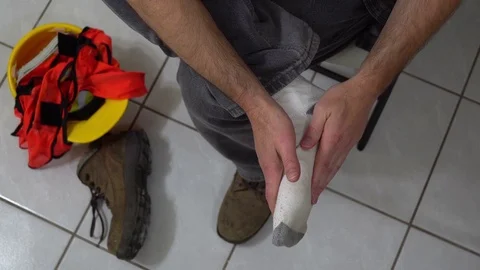 Man Massages Foot Workboot Off Overhead Video stock 72010347