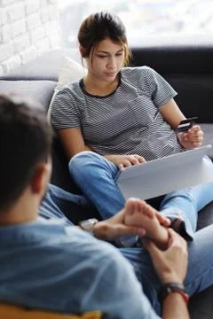 Man Massaging Girlfriend Using Computer On Sofa Stock Photos